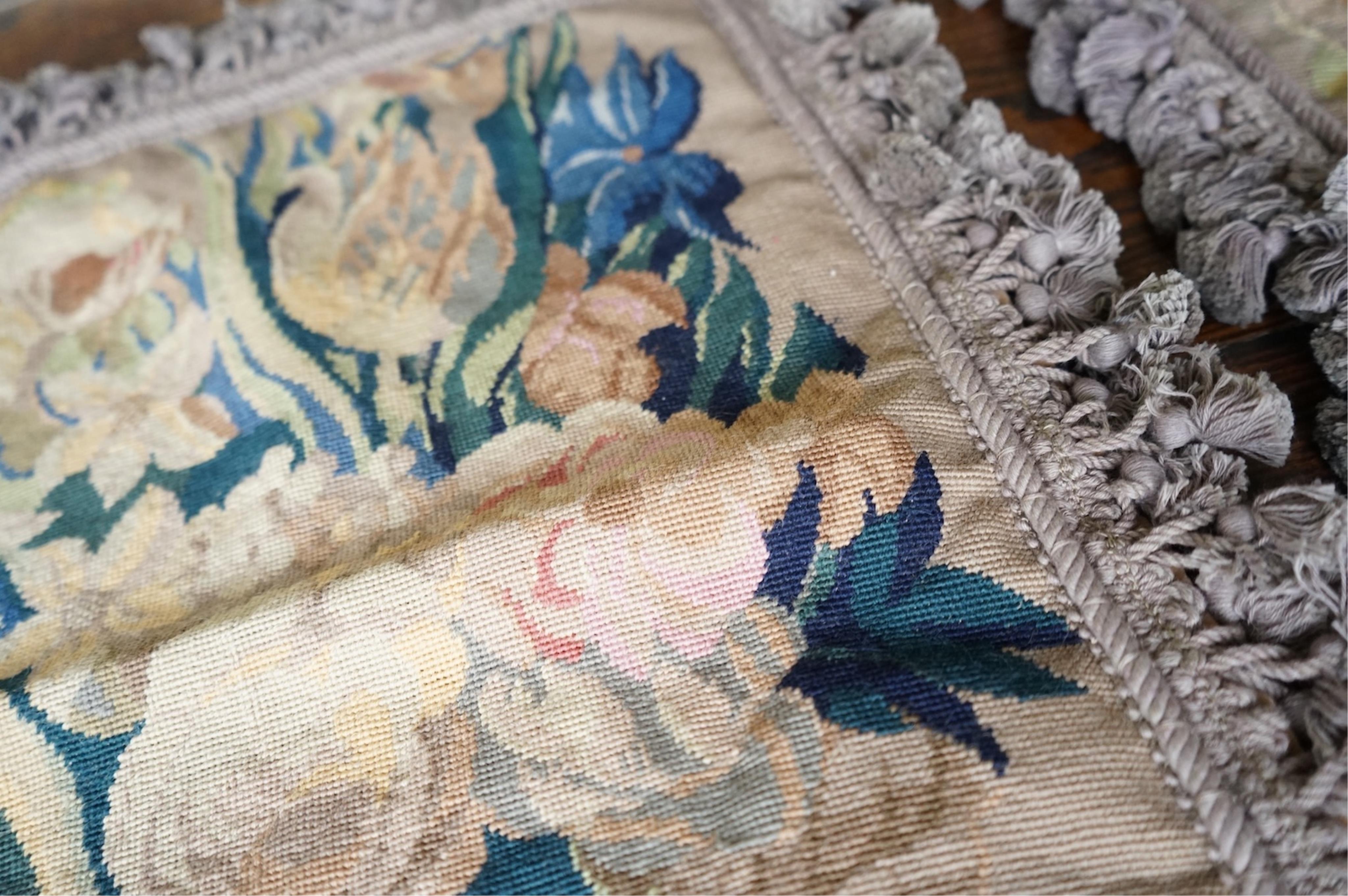 Four large rectangular wool worked cushion covers, with a still life design of a bowl of roses, tulips and daffodils. Embroidered in very muted colours, with ornate tasseled braid and velvet backing. 48cm high x 39cm wid